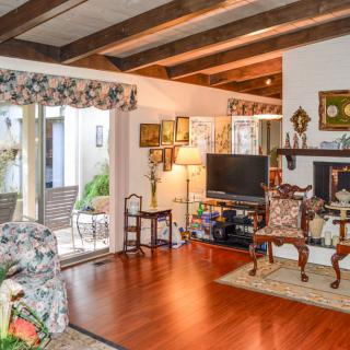 A cozy living room with exposed wooden beams and a stylish interior featuring a television, fireplace, and elegant furniture.