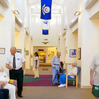 Elderly residents and staff in a nursing home hallway.
