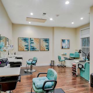A modern salon interior with stylish chairs, mirrors, and decorative artwork.