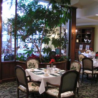 Elegant restaurant interior with dining tables and lush greenery.