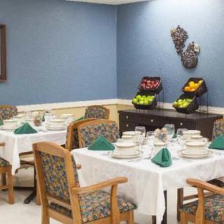 A neatly arranged dining area with tables set for a meal, featuring decorative fruit baskets against a blue wall.