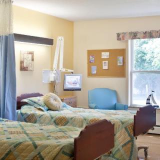 A shared hospital room with two beds, a curtain divider, and a large window.