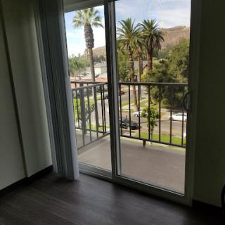 A cozy room with a balcony offering a view of palm trees and greenery.
