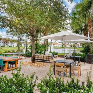 A serene outdoor restaurant patio with tables and chairs under trees and an umbrella.
