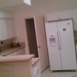 A kitchen with white cabinets and a side-by-side refrigerator.