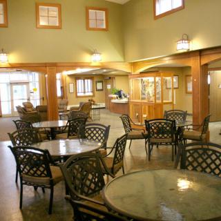 A cozy dining area with round tables and wicker chairs, warmly lit by ceiling lights.