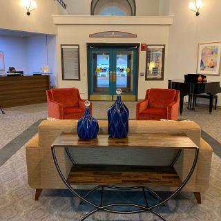 A modern lobby with stylish furniture, featuring red chairs, a sofa, and decorative blue vases on a wooden table.