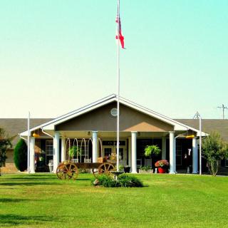 A building with a prominent entrance featuring columns and a flagpole in front, surrounded by a well-maintained lawn.