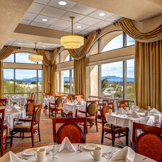 A beautifully set dining room in a restaurant with large windows offering scenic views.