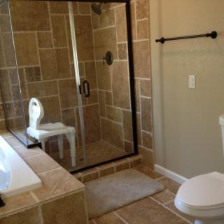 A modern bathroom with a tiled shower, bathtub, and toilet.