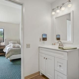 A cozy bedroom with an adjoining bathroom featuring a white vanity and mirror.
