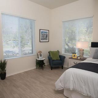 A cozy bedroom with large windows, a comfortable chair, and modern decor.