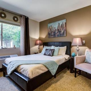 A cozy and stylish bedroom featuring a comfortable bed, warm lighting, and a modern aesthetic.