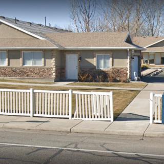 A suburban house with a white fence and a neatly maintained lawn.