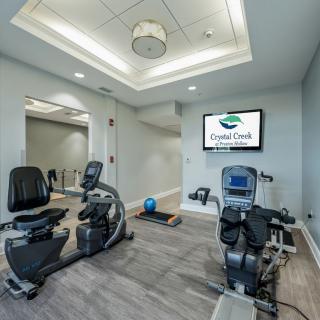 A modern gym room with fitness equipment including exercise bikes and a treadmill, featuring sleek interior design.