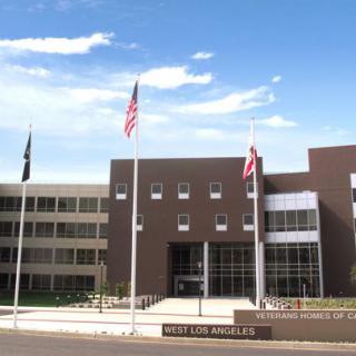 A modern building entrance adorned with multiple flags under a clear blue sky.