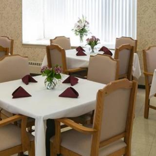 Elegant dining area with neatly arranged tables and chairs, featuring white tablecloths and decorative flowers.
