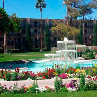 A tranquil garden scene with a central fountain surrounded by colorful flowers and lush greenery.