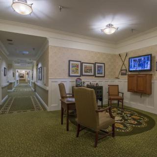 A cozy hallway with seating and decor, featuring a television and framed paintings along the walls.