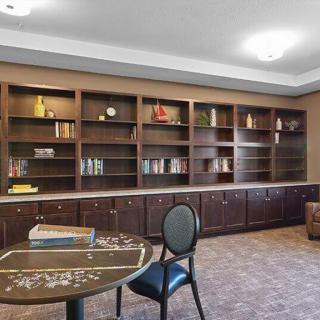A cozy library room with bookshelves, a table, and a chair.