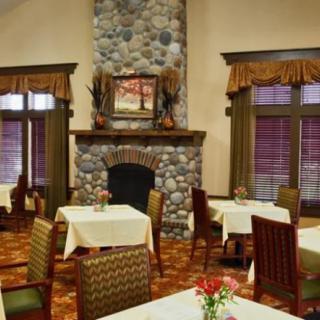 A cozy dining room with a stone fireplace, neatly arranged tables, and warm decor.