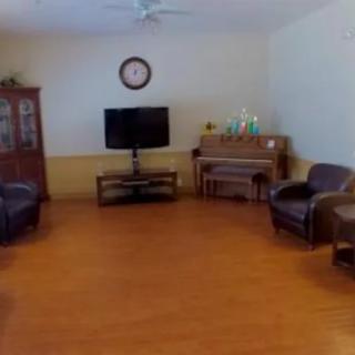 A spacious living room featuring a television, piano, and comfortable seating.
