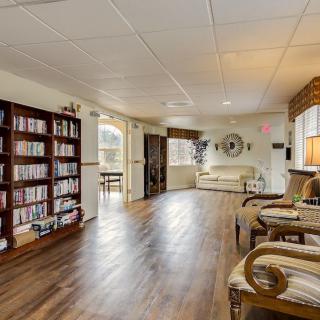 A cozy living room with hardwood floors, furnished with a bookshelf and comfortable seating.