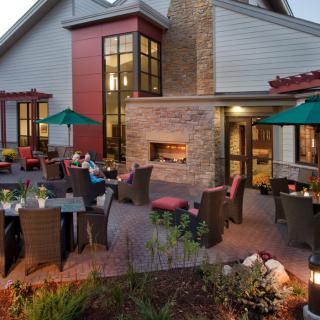 A cozy outdoor restaurant patio with a fireplace and umbrella-covered tables.