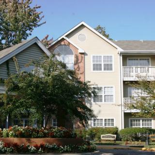 A residential apartment building surrounded by greenery and trees.