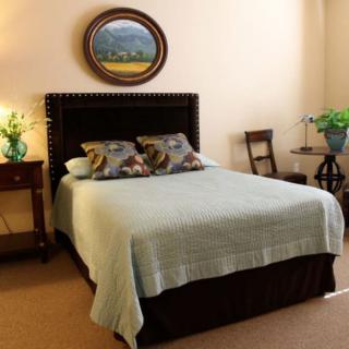 A cozy bedroom with a neatly made bed, decorative pillows, and warm lighting.
