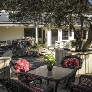 A cozy outdoor patio with a table and chairs surrounded by lush greenery.