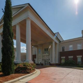 A large building with prominent columns and a covered entrance on a sunny day.