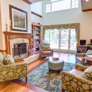 A cozy living room featuring a fireplace, patterned furniture, and large windows with elegant drapes.