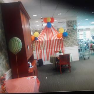 A festive indoor setting decorated with colorful balloons and a striped tent, perfect for a celebration.