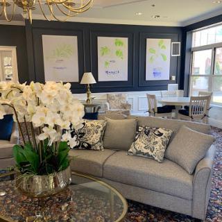 A beautifully designed living room featuring a light gray sofa, decorative pillows, and elegant floral arrangements.