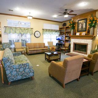 A cozy living room with sofas, chairs, a fireplace, and bookshelves.
