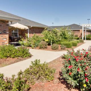 A landscaped garden with pathways and a brick building in the background.