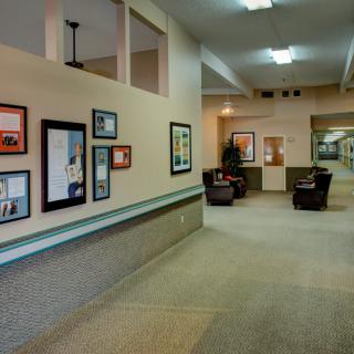 A spacious hallway with framed artwork on the walls and a seating area with chairs.