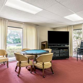 A cozy living room with a TV, round table, and chairs by large windows.