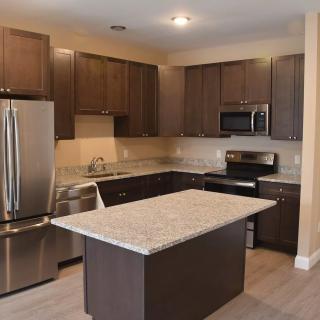 A modern kitchen with dark cabinets, a central island, and stainless steel appliances.