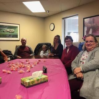 A cheerful group gathered for a celebration in an office setting, surrounded by festive decorations.