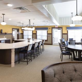 A modern lounge area with seating and dining tables, well-lit by overhead lights.