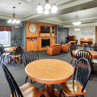 A cozy communal living space featuring wooden tables and chairs, a sofa, and a television set.