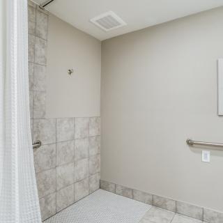 A minimalist bathroom featuring a tiled shower area and a grab bar.