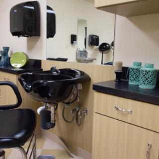 A hair salon interior featuring a washing station with a black sink and chair.