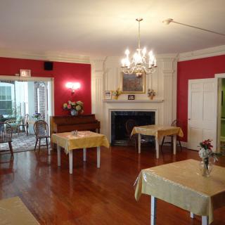 A cozy dining room with red walls, wooden floors, and yellow tablecloths.