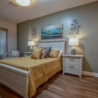 A cozy bedroom featuring a stylish bed with golden bedding, flanked by two nightstands and decorative lamps.