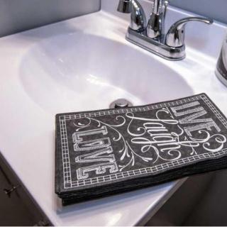 A bathroom sink with a decorative towel displaying the words 'Live Laugh Love'.