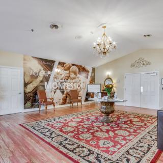 A tastefully decorated room with a chandelier, artwork on the wall, and a patterned carpet.