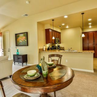 A modern open space dining area connected to a kitchen, featuring a round table set for two.
